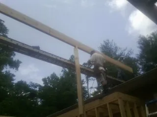 Carpenter setting a ridge beam over a new addition frame — Ice Dam Removal by Roofing Brothers in Huddleston