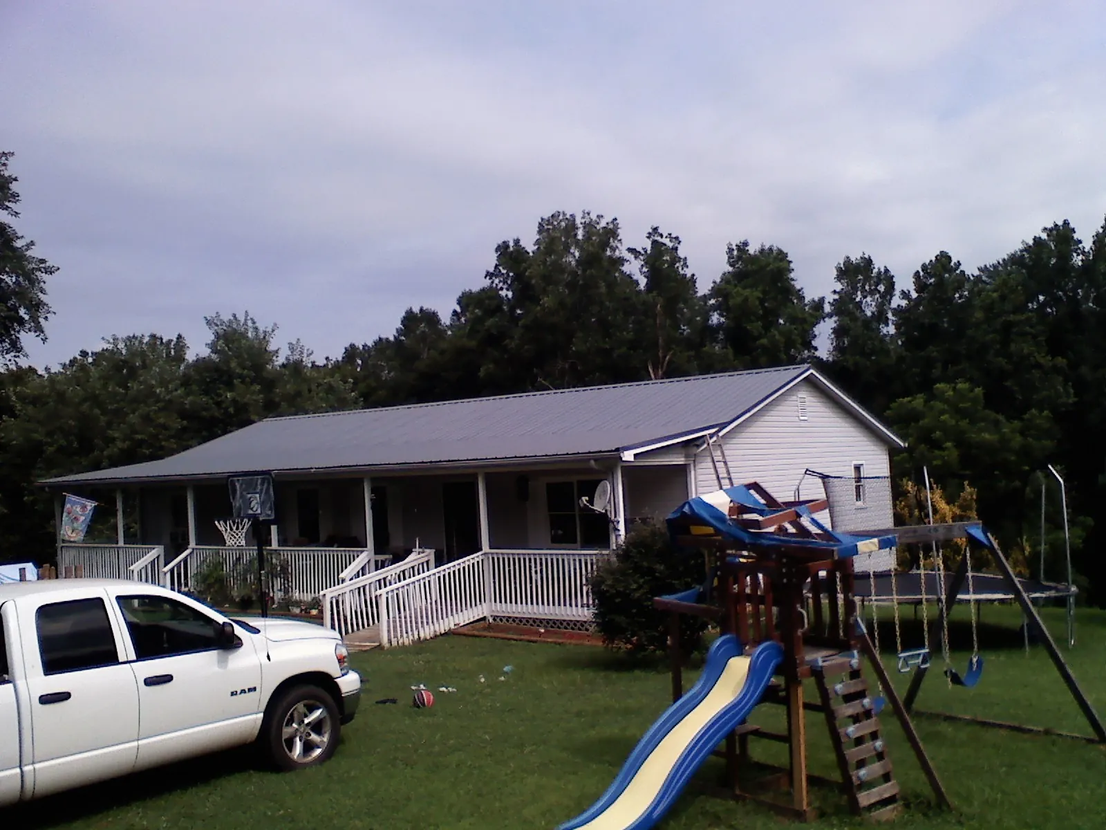 Dark metal roof on a country home with a full length front porch in Huddleston