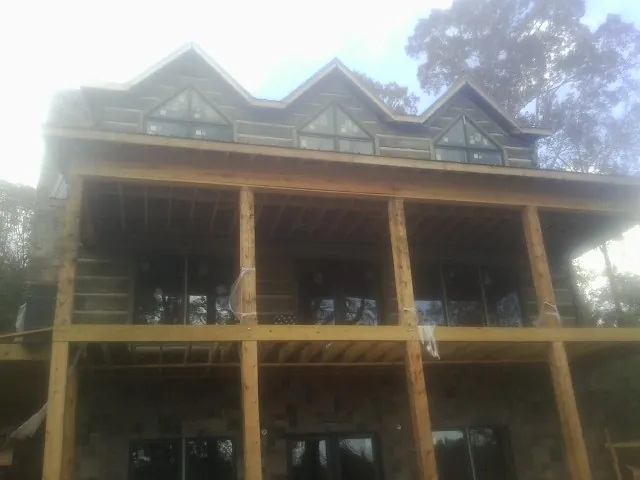 Dormers and porch framing on a large log home under construction — Roof Coating work by our crew in Huddleston