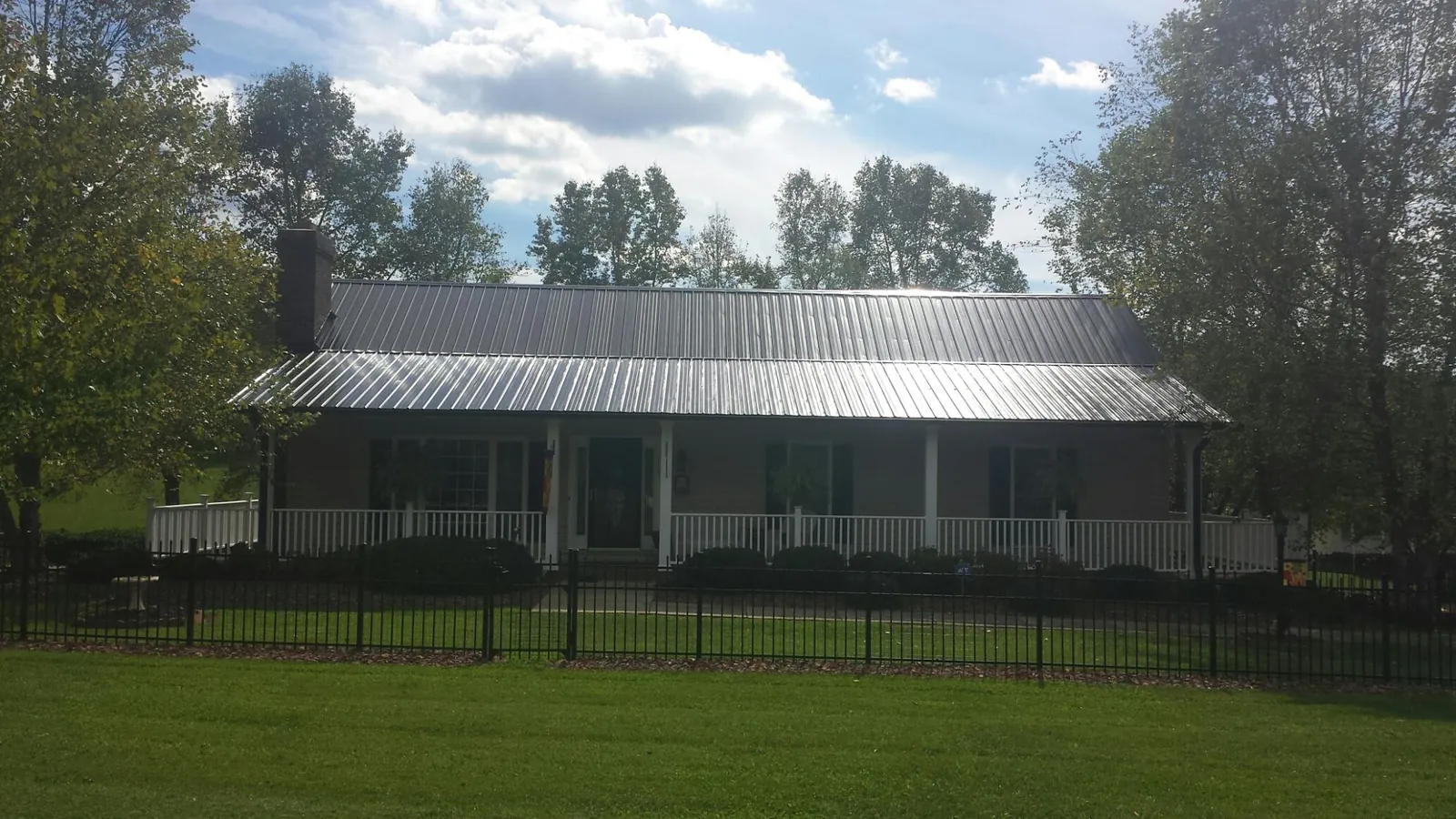 Gray metal roof on a brick ranch with a full width front porch — Gutter Guard Installation work by our crew in Huddleston