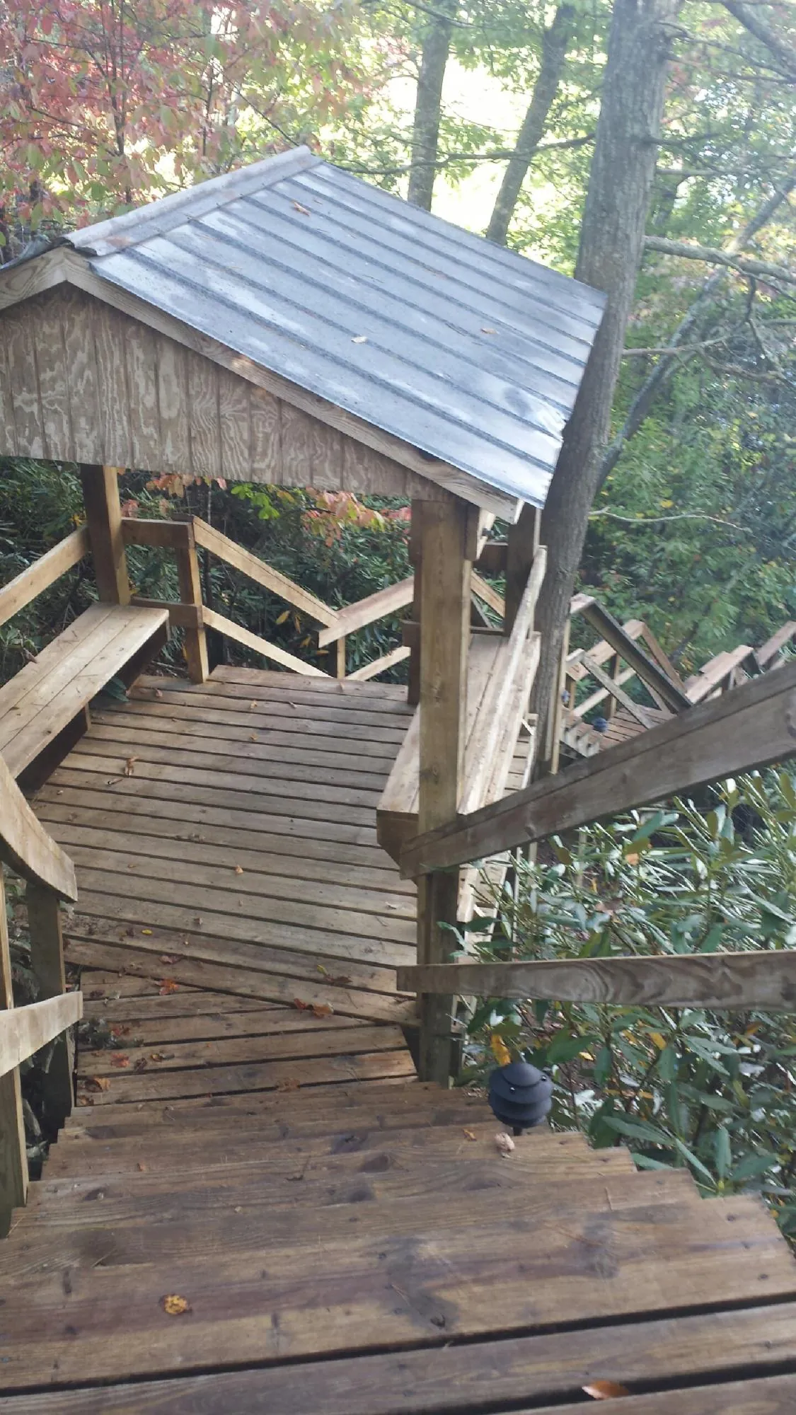 Metal roofed shelter over wooden steps on a wooded walkway — Skylight Repair & Installation work by our crew in Huddleston