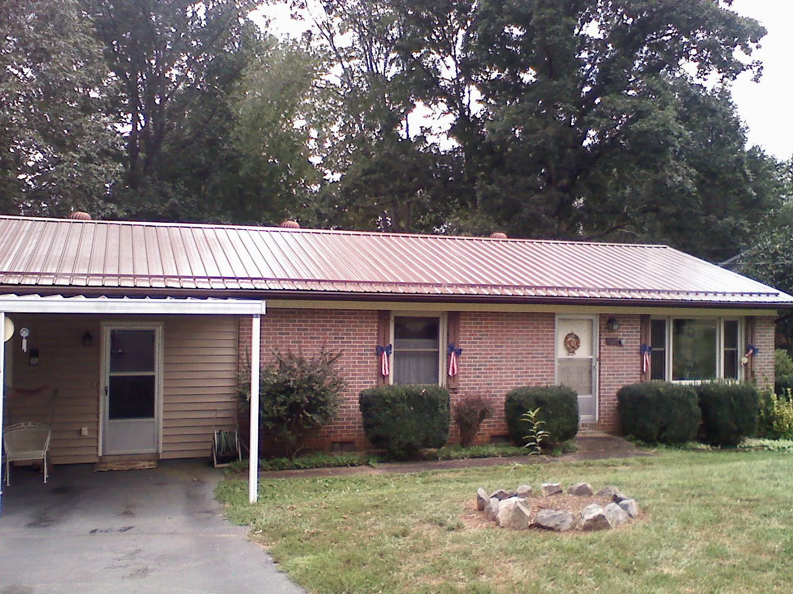 Bronze metal roof and carport on a brick ranch home — Roof Repair work by our crew in Huddleston