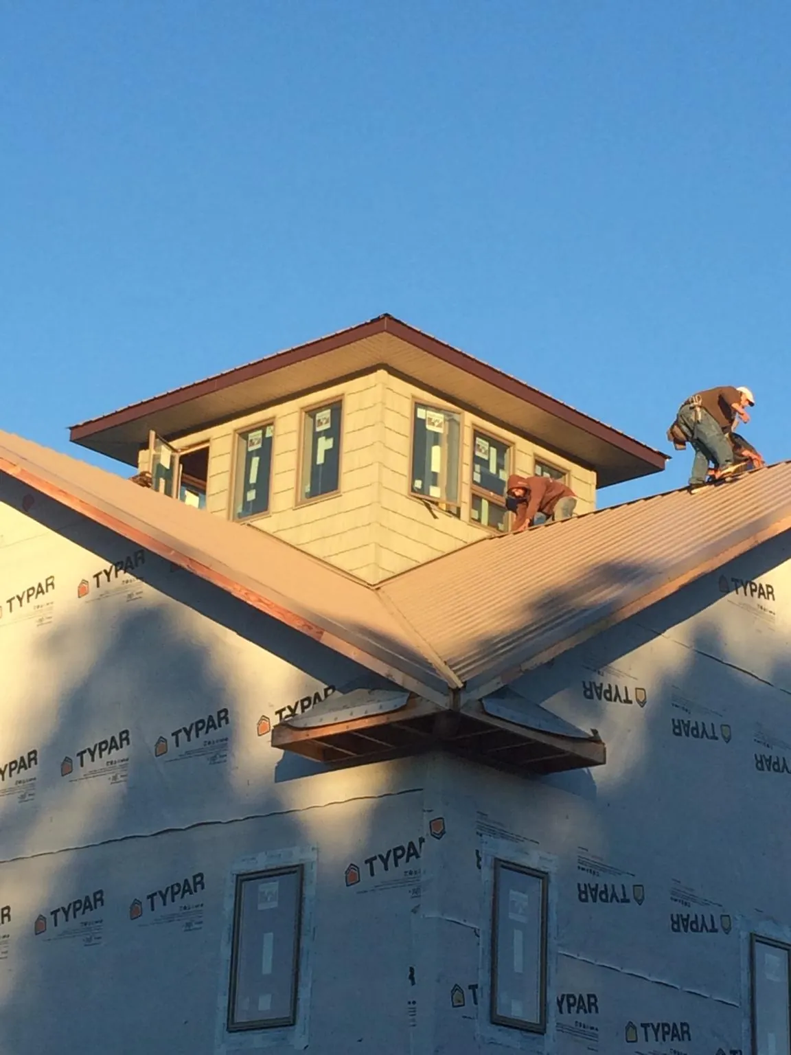 Roofers working around a rooftop cupola on a new metal roof at sunset — Roof Waterproofing in Huddleston by Roofing Brothers